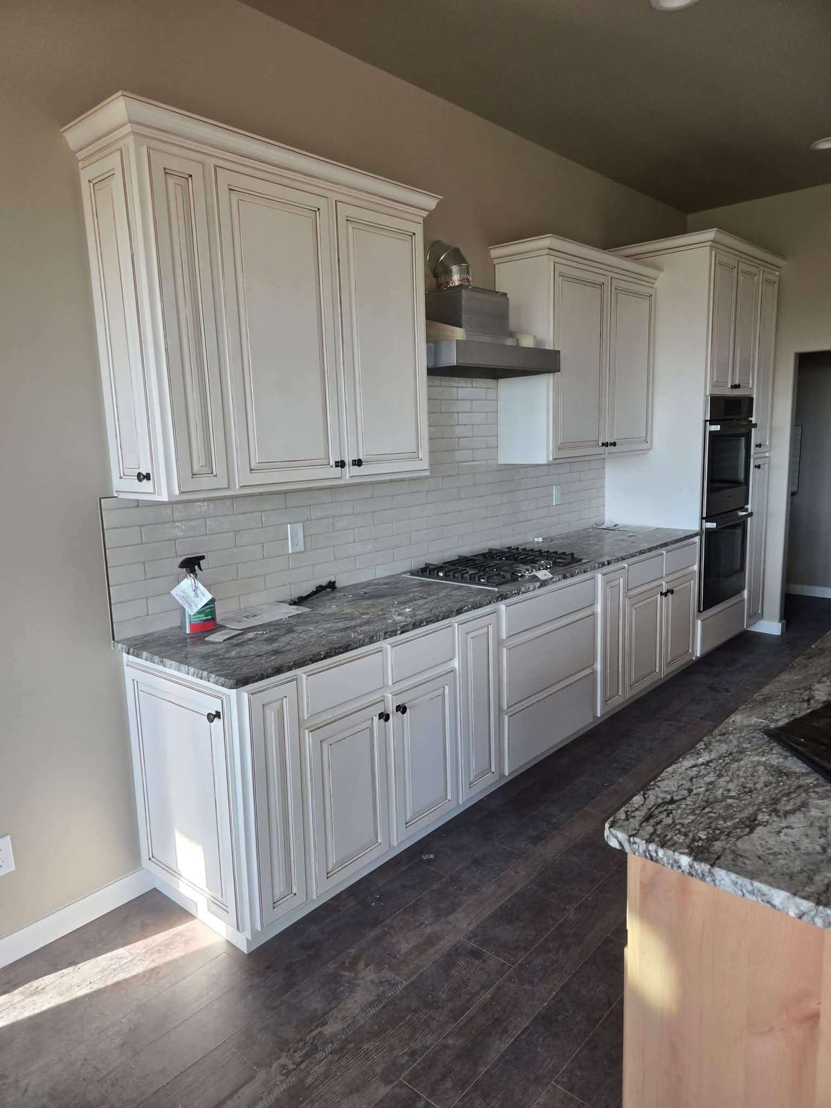 Glazed cream kitchen cabinets with crown molding, granite countertops, and a gas cooktop