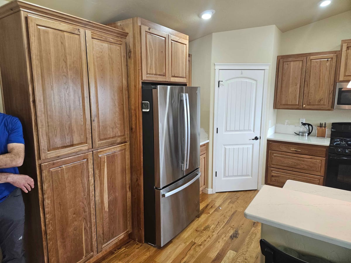 Floor to ceiling rustic cherry pantry cabinets built around a stainless refrigerator